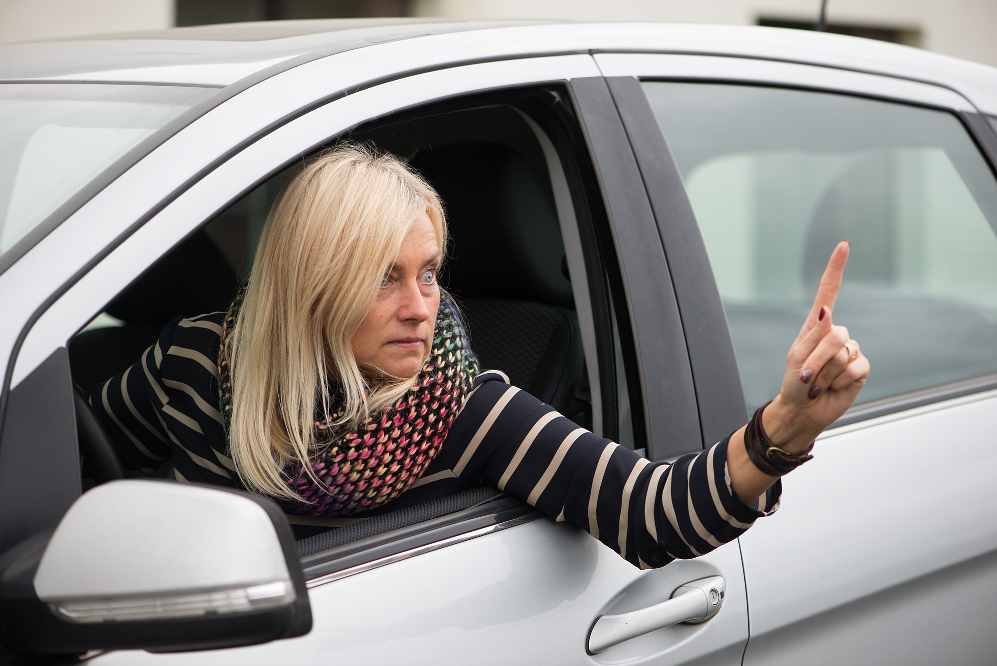 An angry mature woman is driving a car